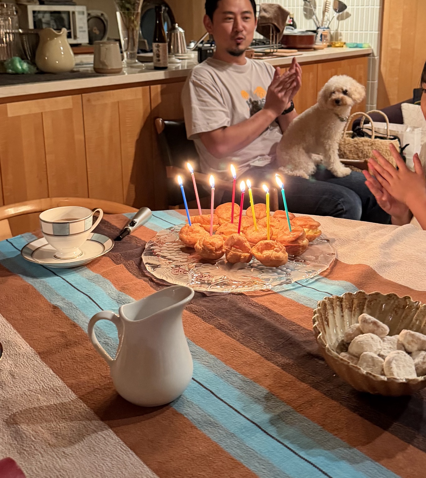 誕生日のろうそくを灯したお菓子を家族で囲む
