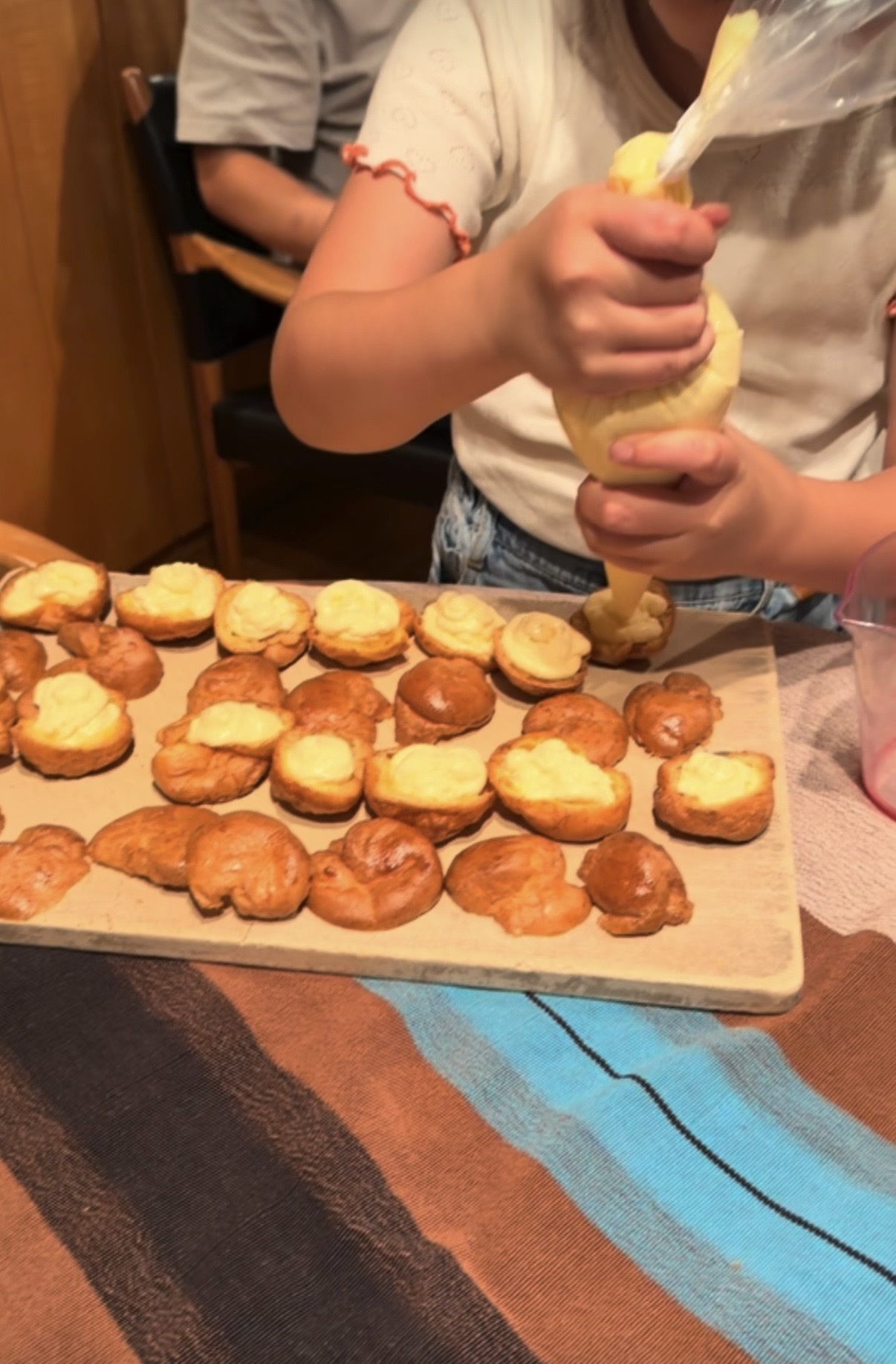 手作りのシュークリームにクリームを絞る孫